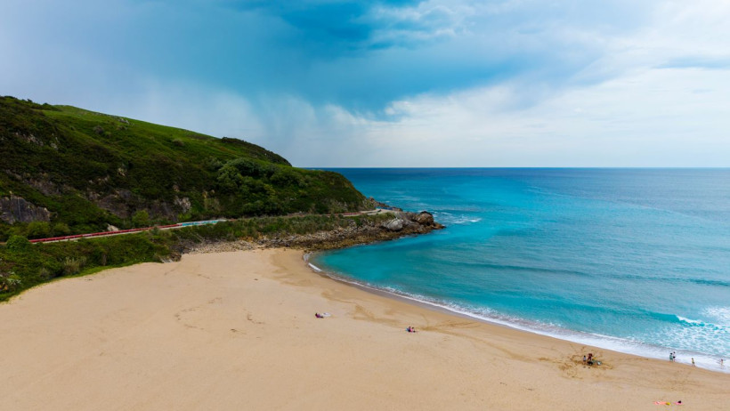 Sandstrand mit türkisem Wasser, grüne Hügel